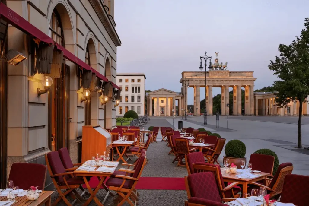 Best hotels in Berlin, the direct view of the monumental Brandenburg Gate from the historic terrace of Brasserie Quarré at Hotel Adlon Kempinski Berlin the most recognizable architectural landmark in the city.