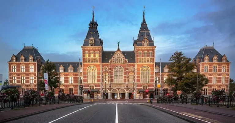 The monumental 19th-century Gothic-Renaissance facade of the Rijksmuseum in Amsterdam, the most recognizable landmark in the Netherlands and the centerpiece for the best historic hotels in the Netherlands.
