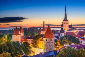 Panoramic view of the medieval Tallinn Old Town wall and red-roofed watchtowers at sunset, located near the best historic hotels in Estonia.