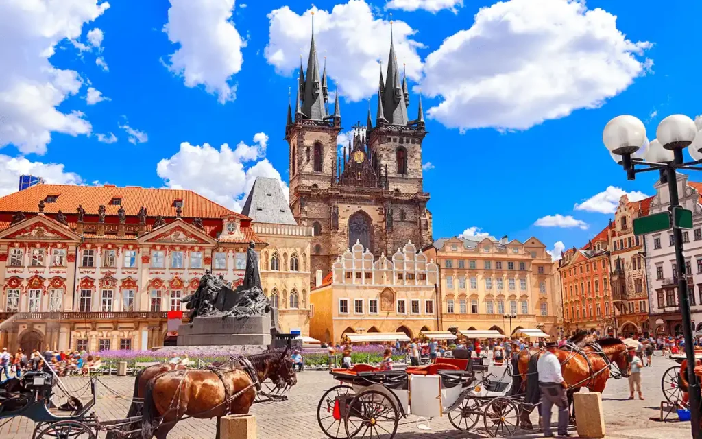 An audit of the best historic hotels in Czech Republic: A vibrant view of the Old Town Square in Prague, featuring the Gothic spires of Týn Church and the Baroque architecture leading toward Prague Castle.