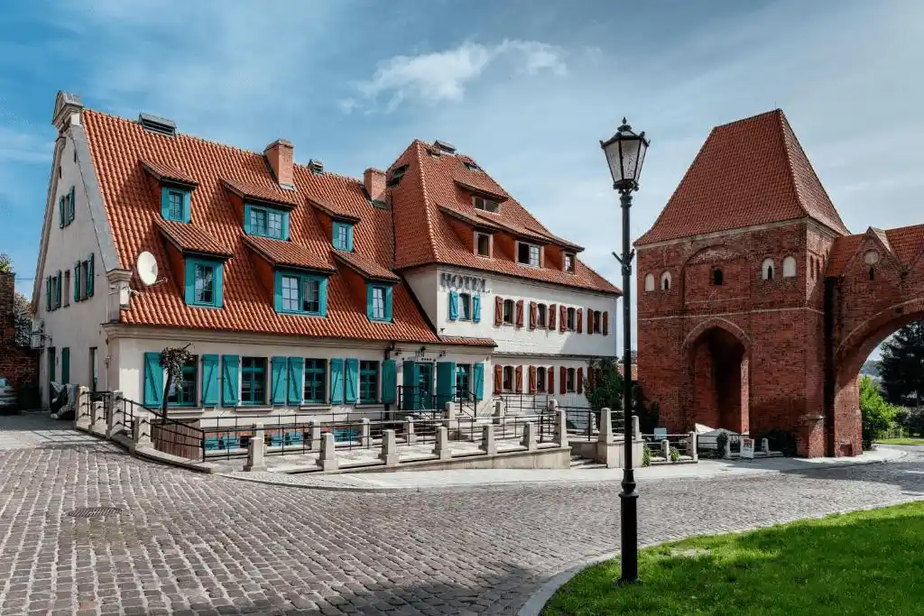 Best hotels in Torun: The authentic 13th-century red-brick facade of Hotel 1231, a restored Teutonic Castle Mill featuring Gothic window rosettes and historic masonry.
