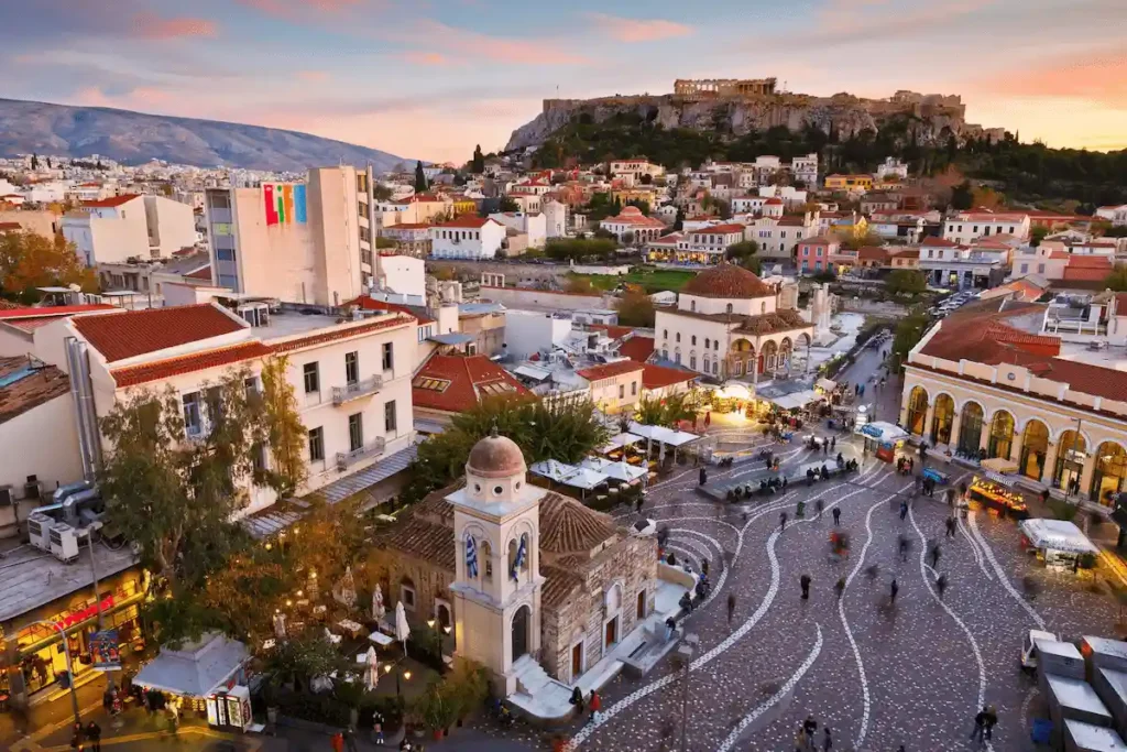 A panoramic sunset view of Monastiraki Square and the Acropolis in Athens, the primary urban hub for the best historic hotels in Greece.