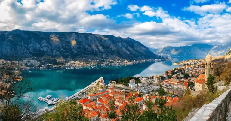 An audit of best historic hotels in Montenegro: A panoramic view of the UNESCO-listed Boka Kotor Bay, featuring the historic stone architecture of Perast and the surrounding fjord-like mountains.