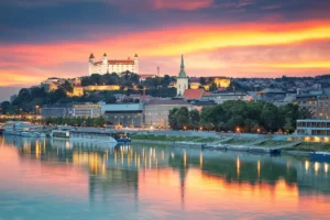 An audit of the best historic hotels in Slovakia: A panoramic view of the Bratislava Castle and the Danube River, representing the imperial heritage of the capital.