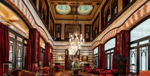 The historic Kubbeli Saloon lobby of the Pera Palace Hotel, featuring the original 1892 wood-latticed domes, turquoise-tinted stained glass, and massive Carrara marble arches that define the best hotels in Beyoğlu Istanbul.