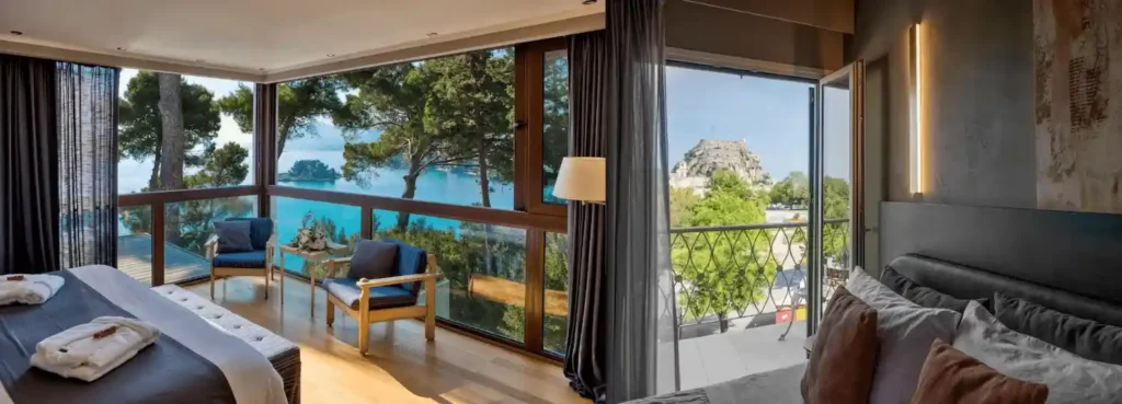 A split-view showcasing the best hotels in Corfu town: a modern bedroom at Corfu Holiday Palace with panoramic sea and Mouse Island views, alongside the UNESCO Old Town and Old Fortress view from a bedroom at Arcadion Hotel.