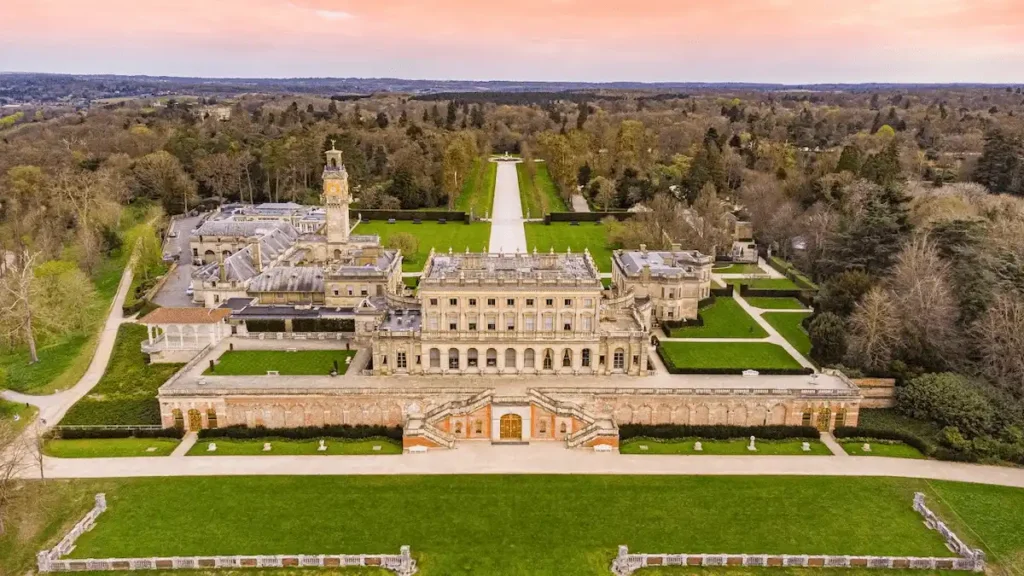 Symmetrical aerial view of the Italianate stone facade and expansive parterre gardens of Cliveden House, representing centuries of elite social and political authority.