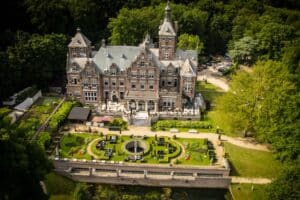 The symmetrical red-brick and stone Classical Revival facade of Landgoed Duin & Kruidberg, featuring grand arched windows and a central portico set within the Dutch National Park dunes.