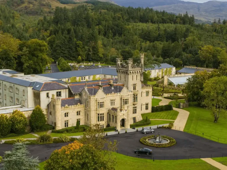 The 19th-century Tudor-Baronial limestone architecture of Lough Eske Castle showcasing its meticulously restored central tower, ornate crenelated battlements, and original defensive stonework.
