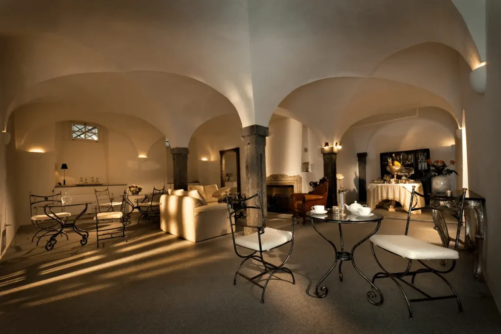 The historic breakfast lounge of Antiq Palace Ljubljana, featuring original 16th-century white vaulted ceilings, stone pillars, and elegant wrought-iron furniture.