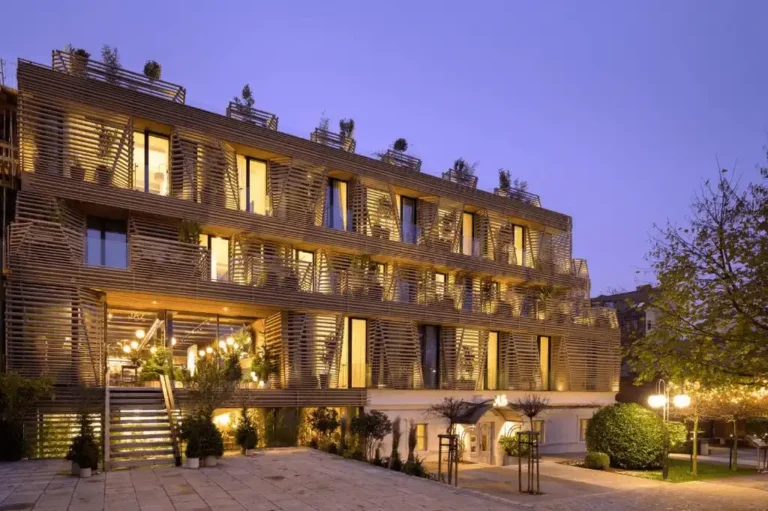 The contemporary timber-slat exterior of AS Boutique Hotel in Ljubljana, designed by OFIS Architects, featuring its signature 'basket' balconies and the destination restaurant Jaz.
