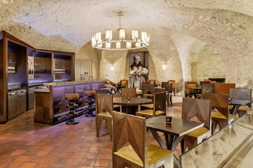 The historic St. Thomas Brewery Bar at Augustine Hotel Prague, featuring original 13th-century stone barrel-vaulted ceilings, terracotta floors, and monastic-inspired contemporary furniture.