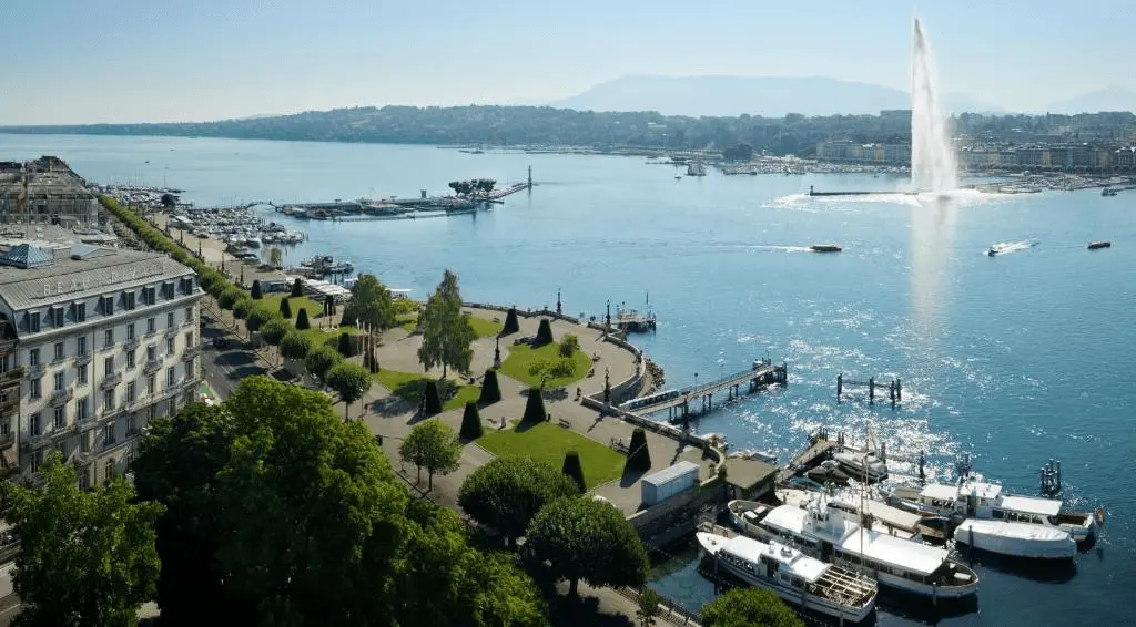 An aerial view of Beau-Rivage Genève overlooking the Lake Geneva promenade and the iconic Jet d'Eau fountain.