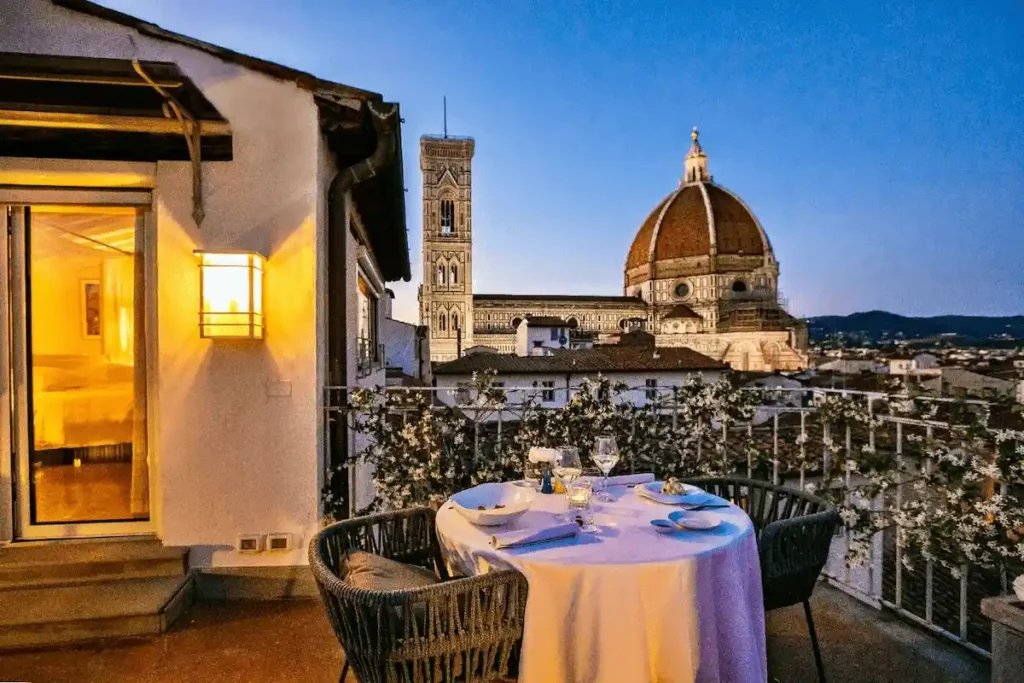 A romantic private terrace at Brunelleschi Hotel Florence set for dinner, offering an unparalleled close-up view of the Florence Cathedral (Duomo) and Giotto's Bell Tower at twilight.