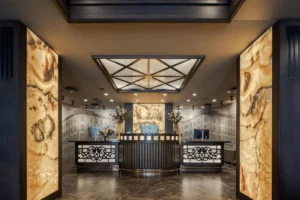 The grand reception area of Eurostars Metropole Riga featuring backlit onyx pillars, dark wood paneling, and a historic mural of the 19th-century facade.
