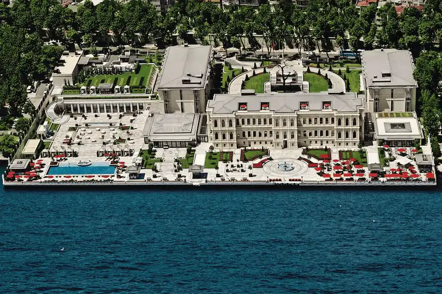An aerial perspective of the Four Seasons Hotel Istanbul at the Bosphorus, highlighting the 19th-century Atik Pasha Palace wing and the expansive marble waterfront terrace with its heated outdoor pool overlooking the strait.