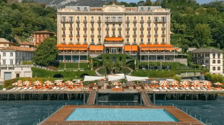 Exterior of the Grand Hotel Tremezzo on Lake Como, a 1910 Belle Époque palace featuring the 'Water-on-the-Water' floating pool and 20,000 square meters of botanical gardens.