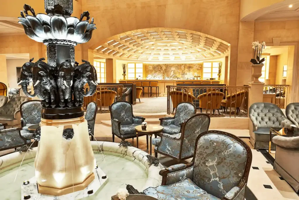The historic Hindu-inspired bronze Elephant Fountain, a 1930s gift from a Maharaja, serves as the centerpiece of the lobby lounge at Hotel Adlon Kempinski Berlin, set against neoclassical arches and a coffered ceiling.