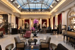 The grand lobby of Hotel Bellevue Palace Bern featuring its famous ornate stained-glass ceiling, marble columns, and velvet furnishings in the official guesthouse of the Swiss government.