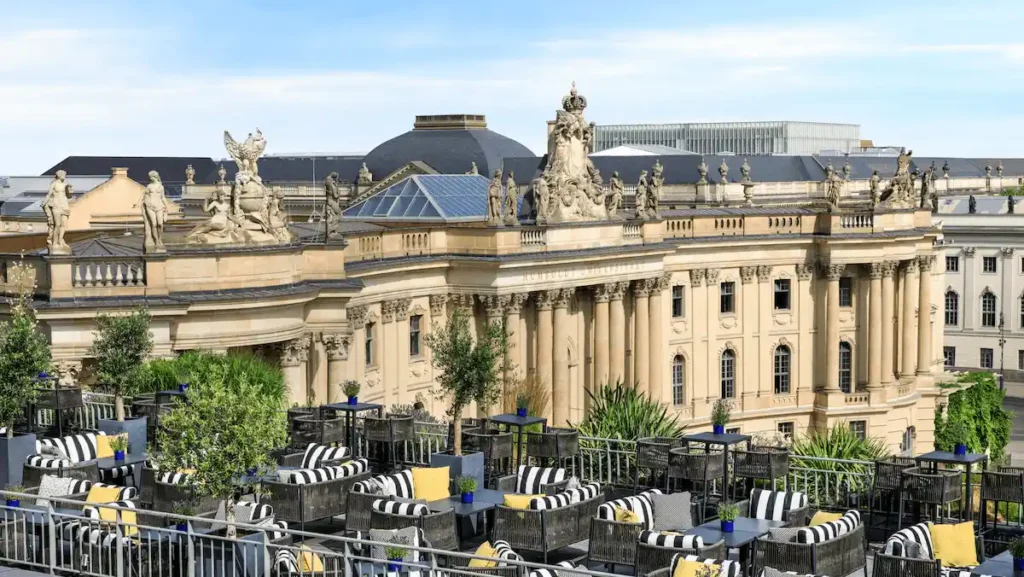 The expansive rooftop terrace of Hotel de Rome Berlin, a Rocco Forte Hotel, featuring stylish lounge furniture and panoramic views over Bebelplatz, the State Opera House, and the historic skyline of Berlin-Mitte.