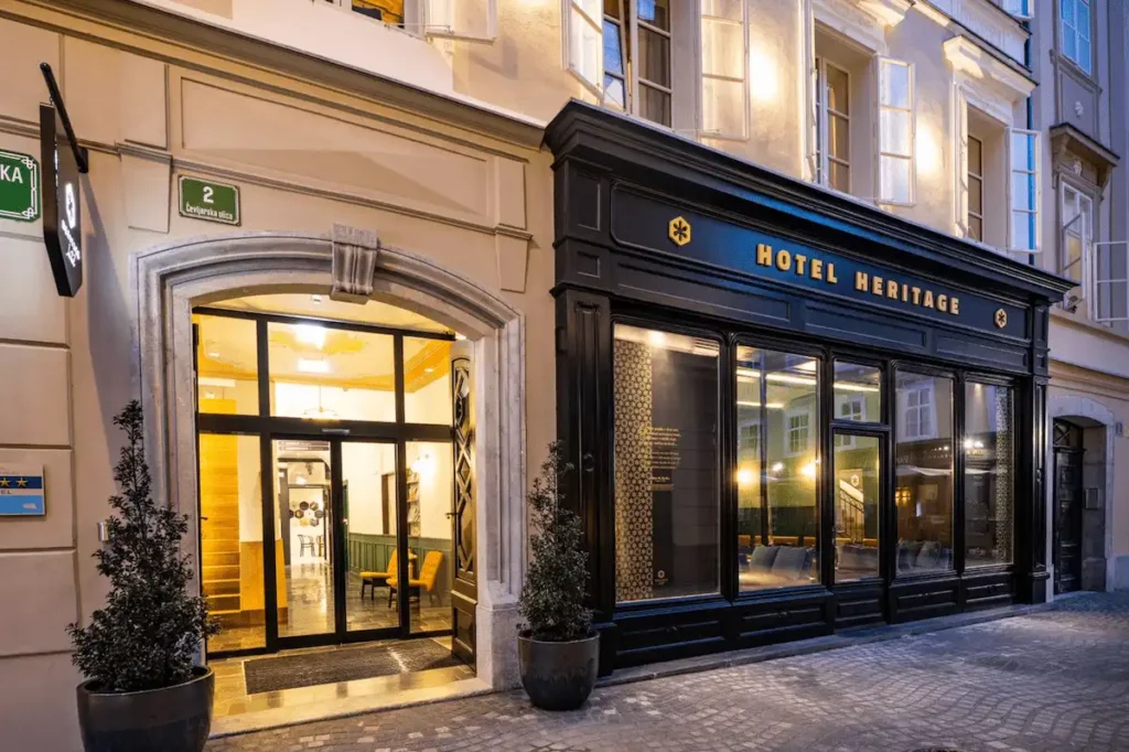 The sleek black-framed modern entrance of Hotel Heritage Ljubljana, integrated into a historic 16th-century Renaissance facade on the city's shortest pedestrian street.