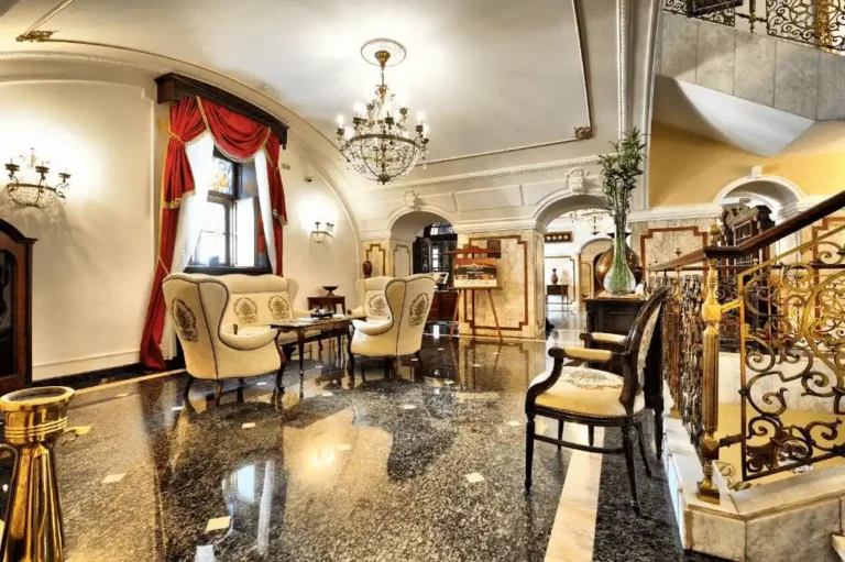 The opulent baroque lobby of Hotel Leopold I in the Petrovaradin Fortress, featuring polished marble floors, classical archways, crystal chandeliers, and imperial-style furniture.