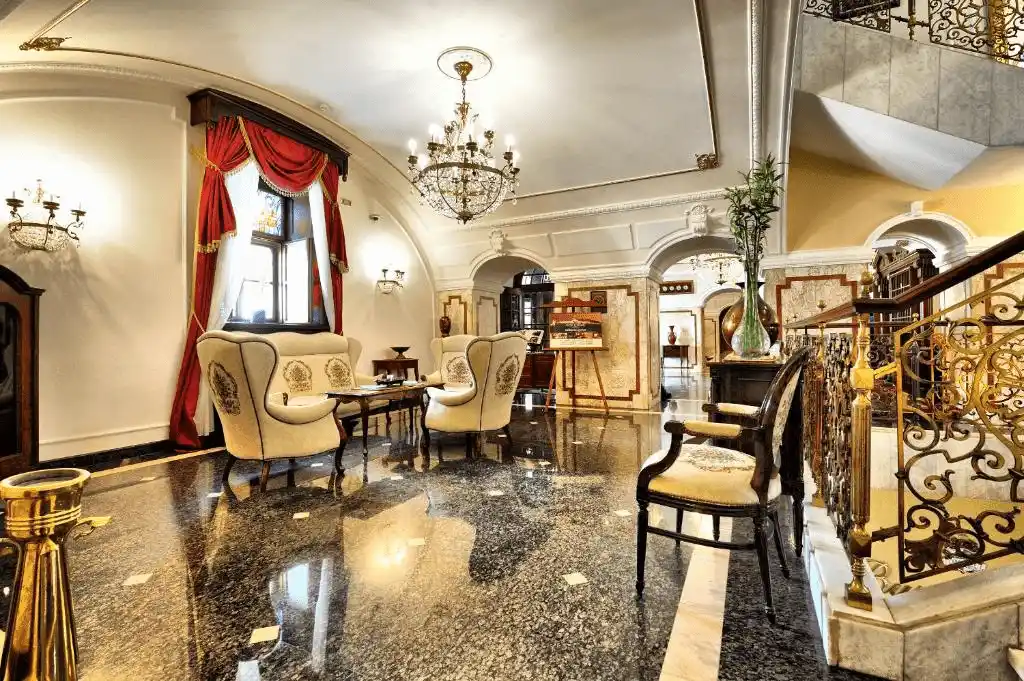 The opulent baroque lobby of Hotel Leopold I in the Petrovaradin Fortress, featuring polished marble floors, classical archways, crystal chandeliers, and imperial-style furniture.