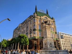The iconic Russian Secessionist facade of Hotel Moskva in Belgrade, featuring its signature emerald green Zsolnay ceramic tiles and architectural towers under a clear blue sky.