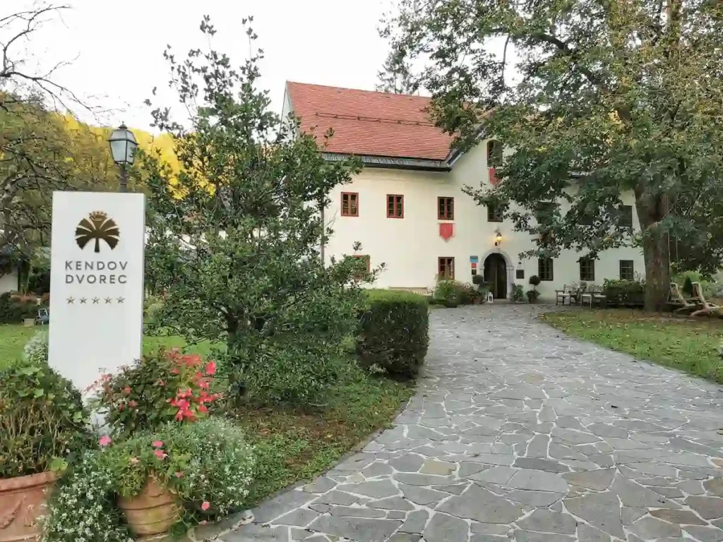 The stone entrance path leading to the white-walled historic manor of Kendov Dvorec, a member of Relais & Châteaux in the Slovenian countryside.