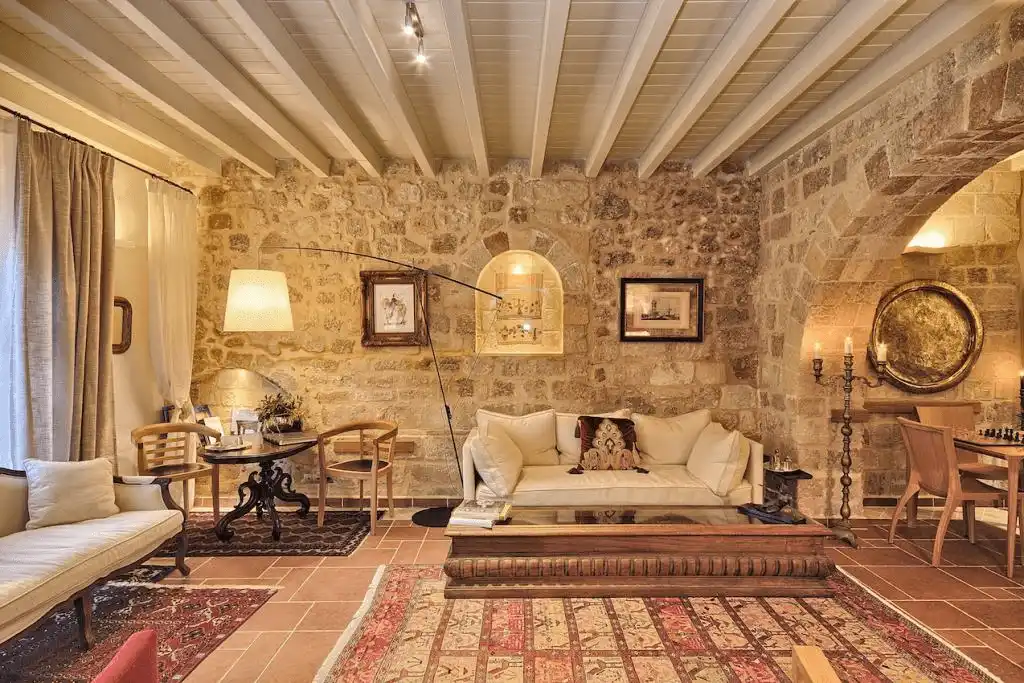 The medieval stone exterior and courtyard of Kókkini Porta Rossa in Rhodes, a 14th-century former Knight's residence turned luxury boutique hotel, situated directly beside the historic St. John’s Gate within the UNESCO-listed Old Town walls.