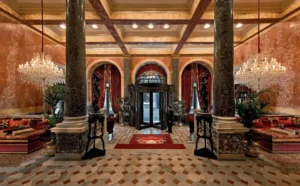 The opulent, neo-classical lobby of the Pera Palace Hotel in Istanbul, featuring massive dark marble columns, ornate crystal chandeliers, and red velvet seating within the 1892 landmark originally built to host passengers of the Orient Express.