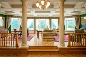 The luxurious Presidential Suite at Spa Hotel Imperial, featuring neoclassical columns, elegant green walls, parquet flooring, and large windows overlooking the Karlovy Vary valley.
