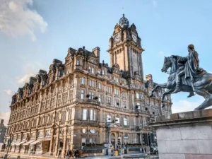 The grand Victorian sandstone facade of The Balmoral Hotel in Edinburgh, featuring its iconic 190-foot clock tower and ornate Scots Baronial architecture, situated at the prominent corner of Princes Street and North Bridge.