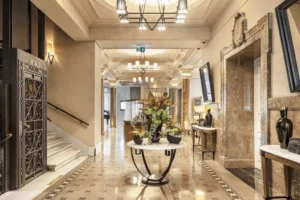 The elegant lobby of The Bank Hotel Istanbul, showcasing a beautifully restored vintage wrought-iron elevator, marble columns, and a sophisticated marble-floored hallway within the former 1867 Credit General Ottoman headquarters.