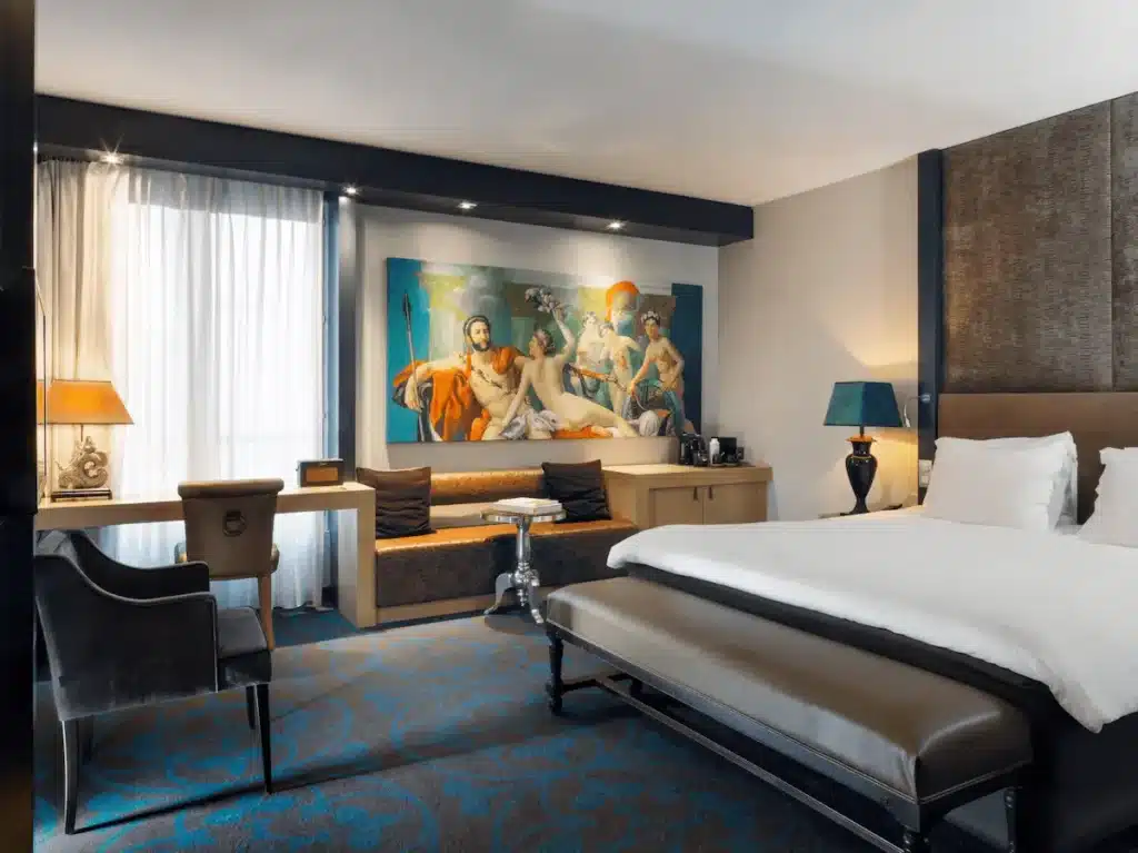 A contemporary guest room at The Dominican Brussels, a Member of Design Hotels featuring a large reproduction of a Jacques-Louis David painting and modern monastic-inspired furniture.