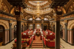 The opulent, double-height dining room at The Merrion Hotel in Dublin, featuring original 18th-century Rococo plasterwork by Robert West, ornate gold-leaf detailing, and a massive crystal chandelier in a building that served as the 1769 birthplace of the Duke of Wellington.