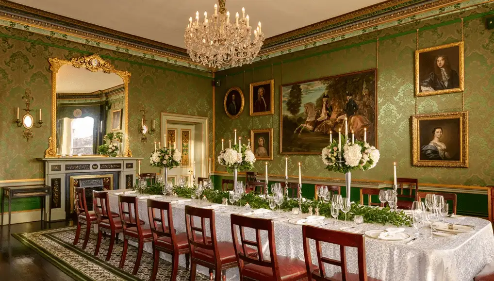 The historic Constitution Room at The Shelbourne Dublin, featuring green damask wallpaper, ornate gold-framed portraits, and the original table where the Irish Free State Constitution was drafted in 1922.