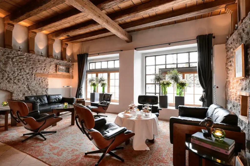 A luxury suite at Widder Hotel Zurich featuring original 14th-century stone walls and wood beams paired with 20th-century designer furniture.