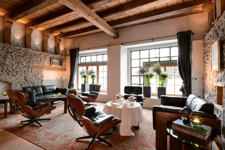 A luxury suite at Widder Hotel Zurich featuring original 14th-century stone walls and wood beams paired with 20th-century designer furniture.